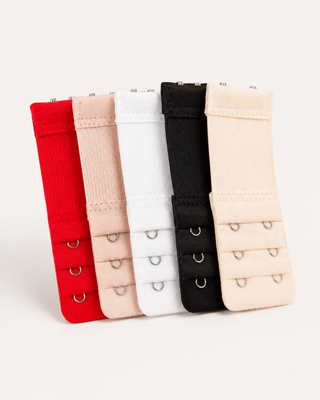 Conjunto de cinco extensores de soutien em vermelho, rosa, branco, preto e bege sobre fundo off-white