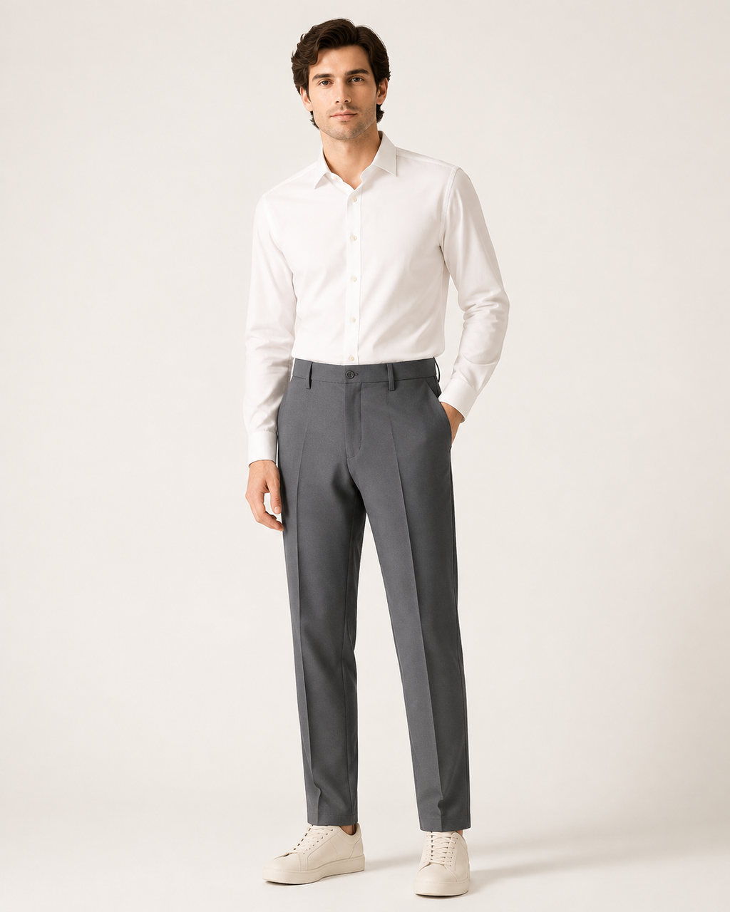 Miesmalli harmaissa kapenevissa slim fit -housuissa vaaleassa studiossa