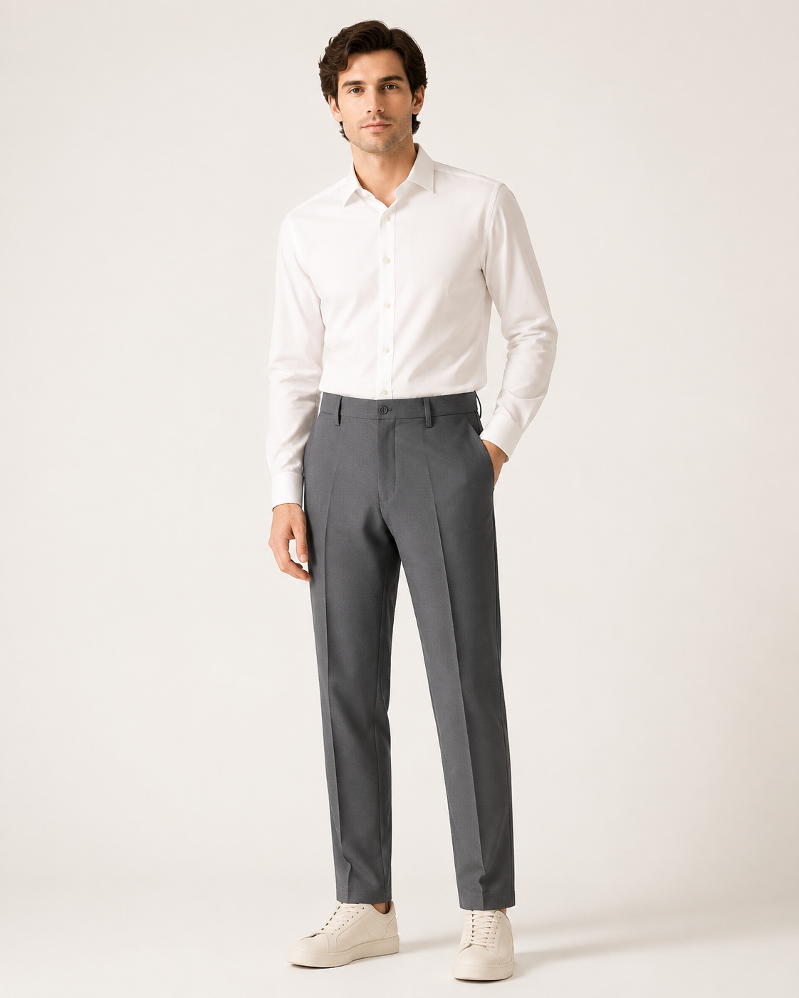Miesmalli harmaissa kapenevissa slim fit -housuissa vaaleassa studiossa