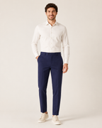 Miesmalli laivastonsinisissä kapenevissa slim fit -housuissa vaaleassa studiossa
