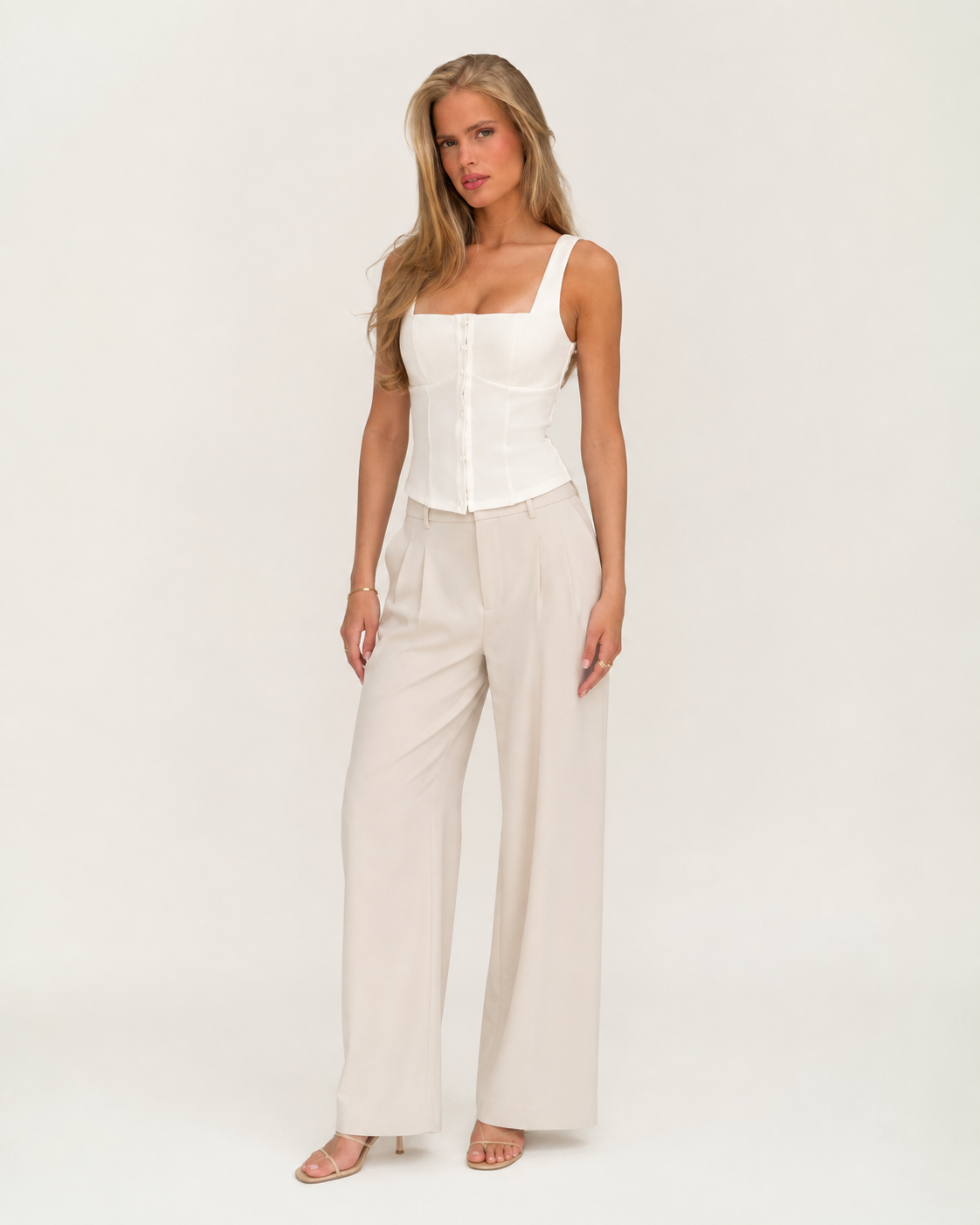 Modelo adulto de corpo inteiro com top branco estruturado de decote quadrado e botões em estúdio off-white