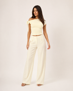 Modelo adulto de corpo inteiro com top Nova amarelo-claro assimétrico e laço no ombro em estúdio off-white